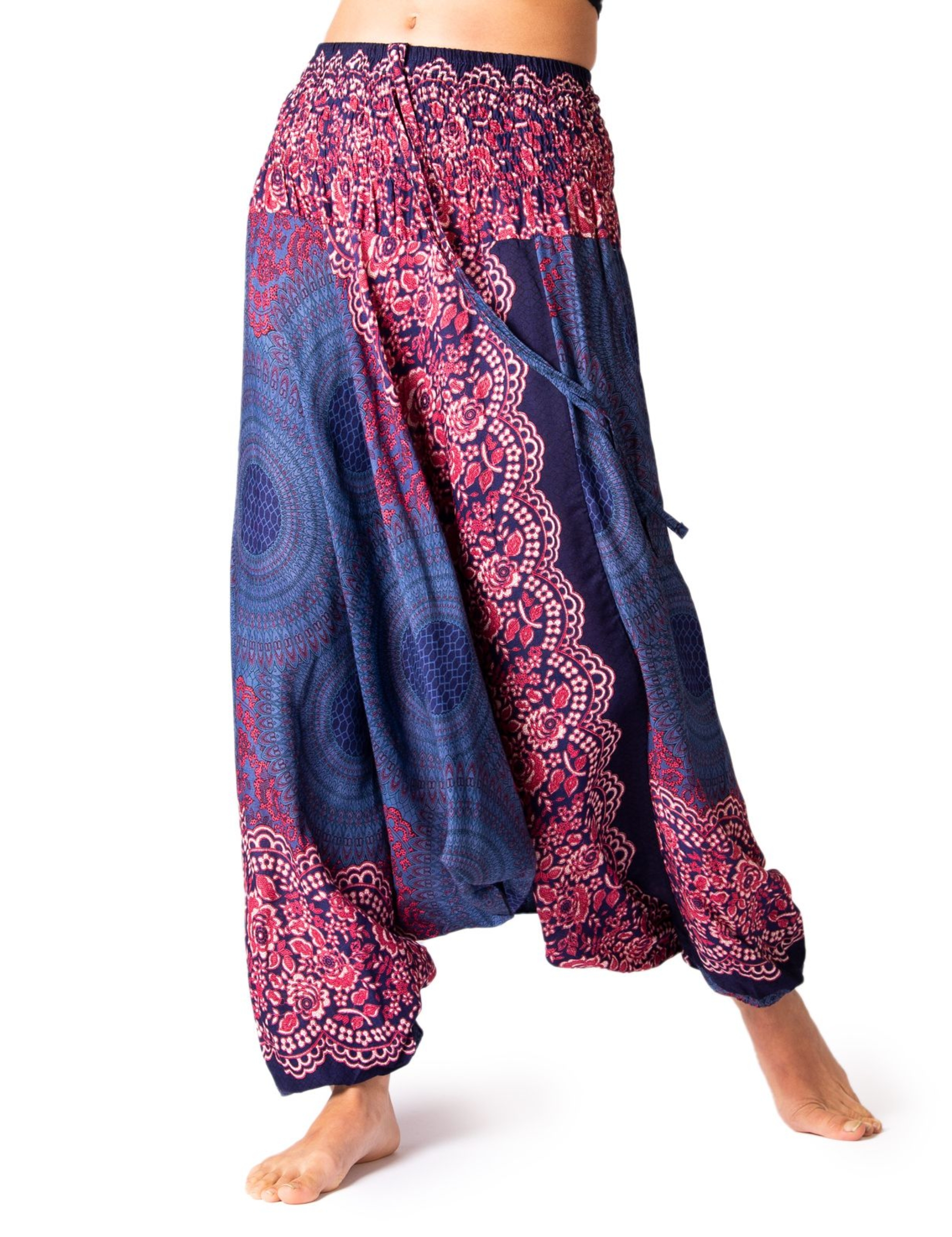 Model trägt PANASIAM Aladinhose Peacock, eine bequeme Damen-Haremshose im Bohemian-Look mit blau-pinkem Pfauenmuster, ideal für Yoga, Tanz, Alltag und Meditation.