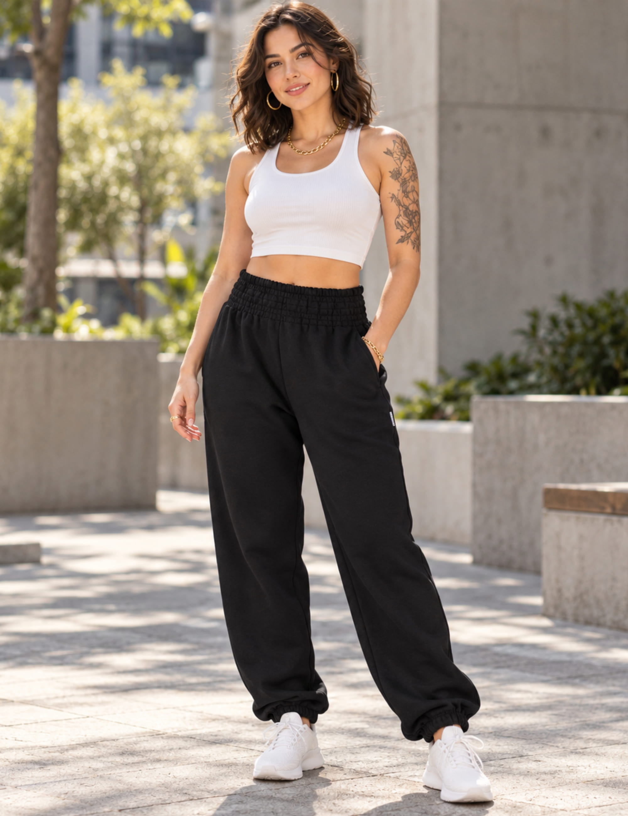 Model wearing PANASIAM women's joggers in 100% cotton, black, with high shirred waistband, relaxed fit and elastic cuffs