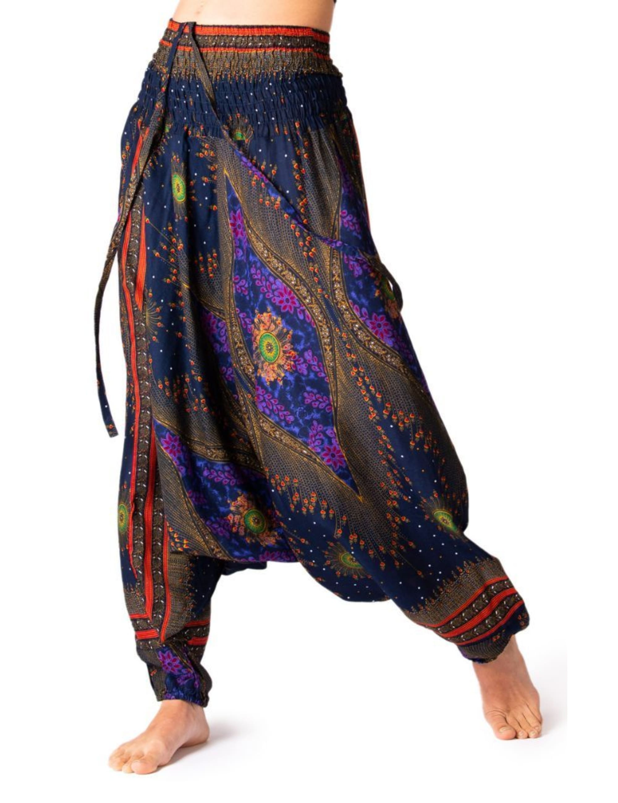 Model trägt die PANASIAM Aladinhose Peacock, eine luftige Boho-Haremshose mit elastischem Bund und buntem Pfauenmuster in Blau für Yoga, Tanz und Freizeit.