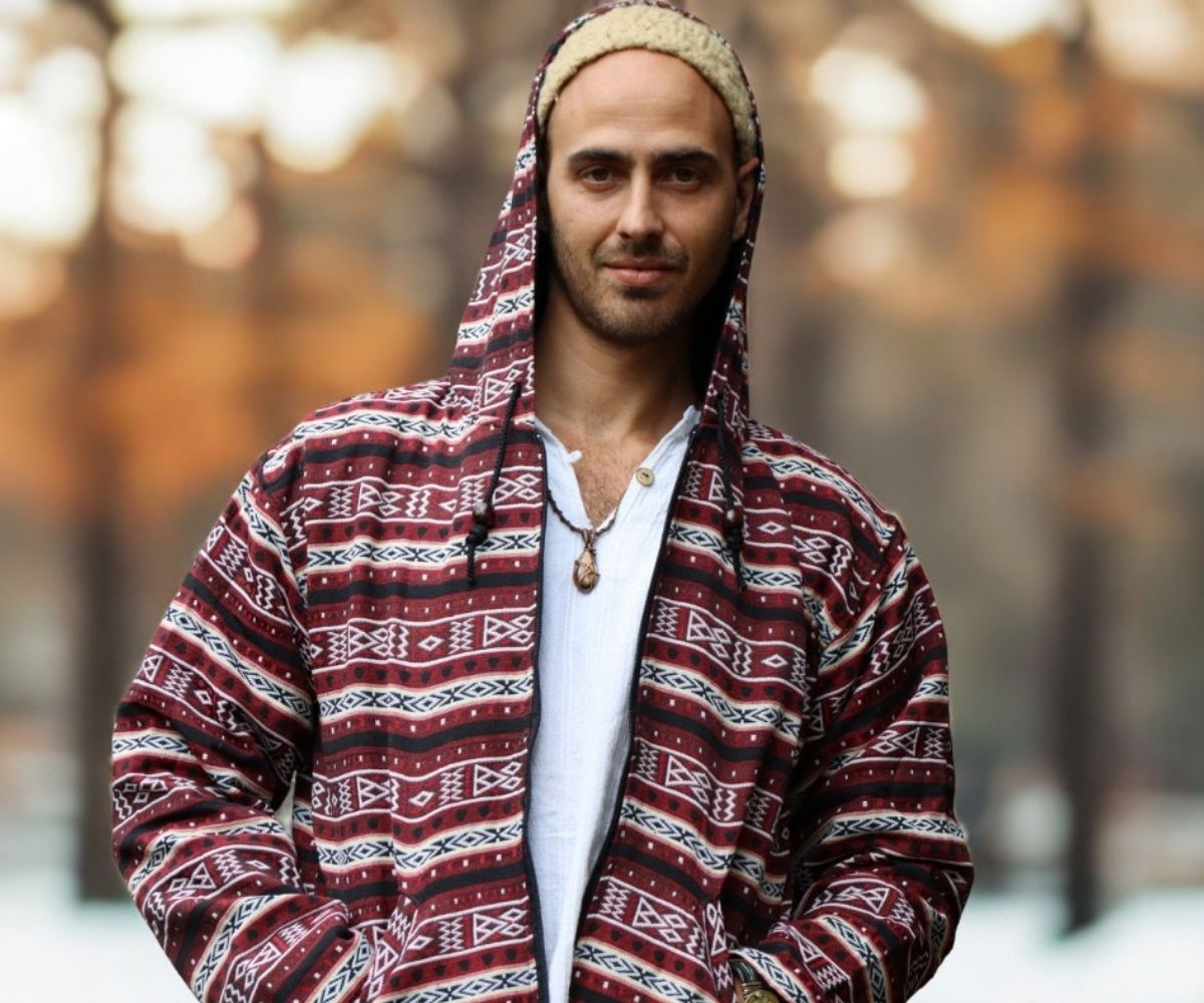 Mann trägt einen bordeauxfarbenen Hoodie-Cardigan mit Ethno-Muster und weißem Shirt im herbstlichen Outdoor-Setting