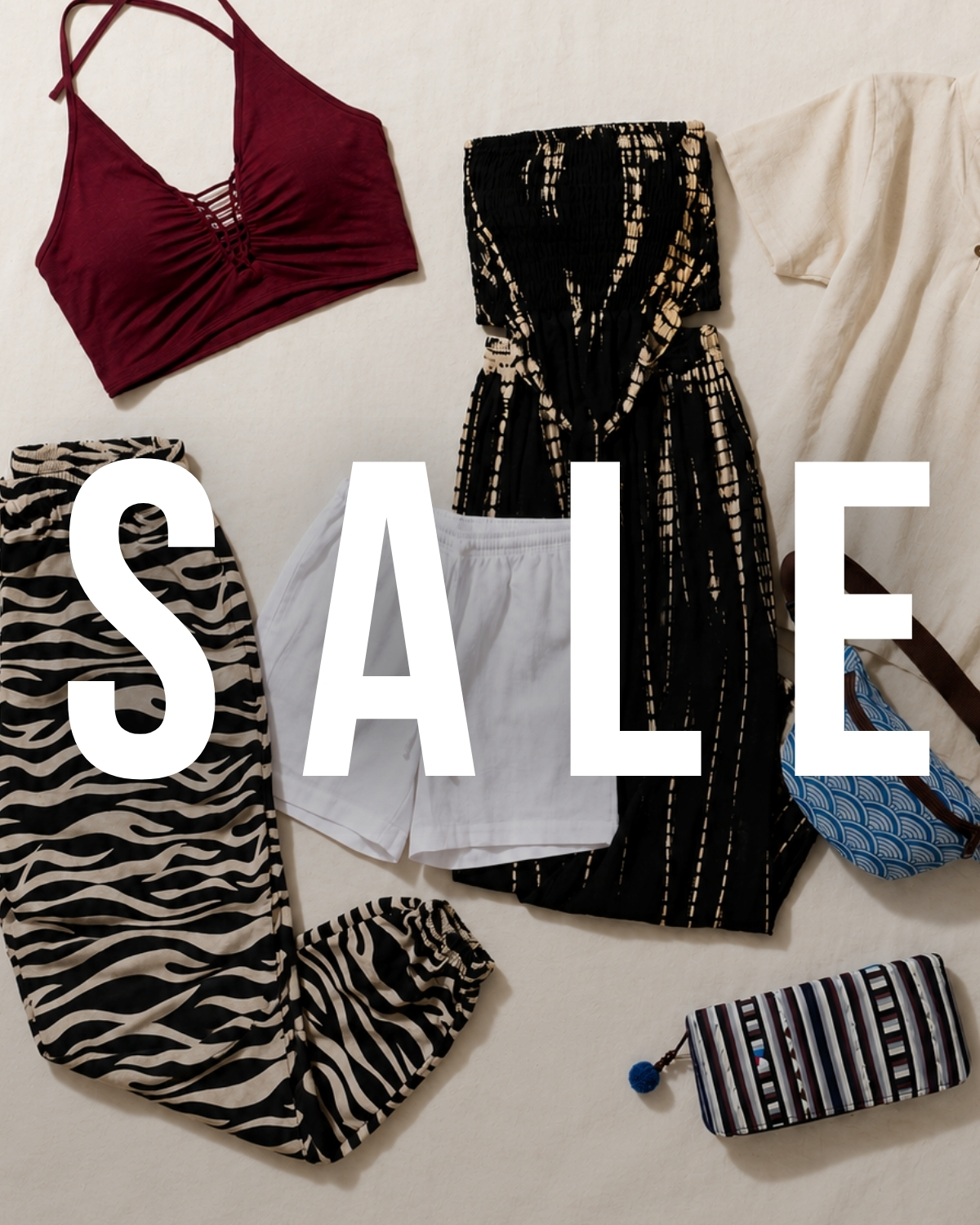 Flatlay einer SALE-Modeauswahl mit bordeauxfarbenem Top, schwarzem Maxikleid, Zebrahose, weißen Shorts und Accessoires