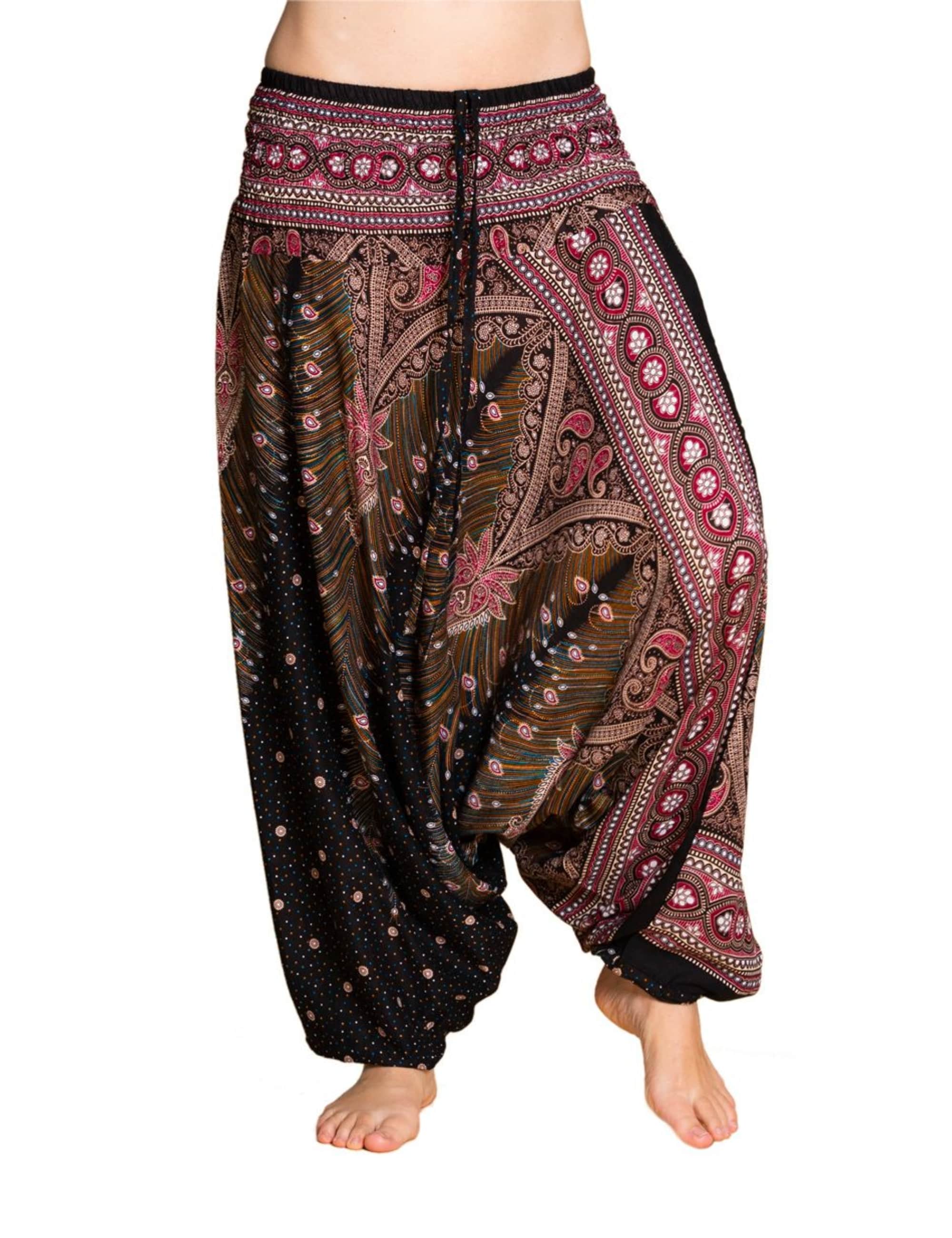Model trägt PANASIAM Aladinhose Peacock mit tiefem Schritt, elastischem Bund und weitem Bein im Boho-Look, schwarz mit Pink, Paisley- und Pfauenfeder-Muster, ideal für Yoga, Tanz und Freizeit.