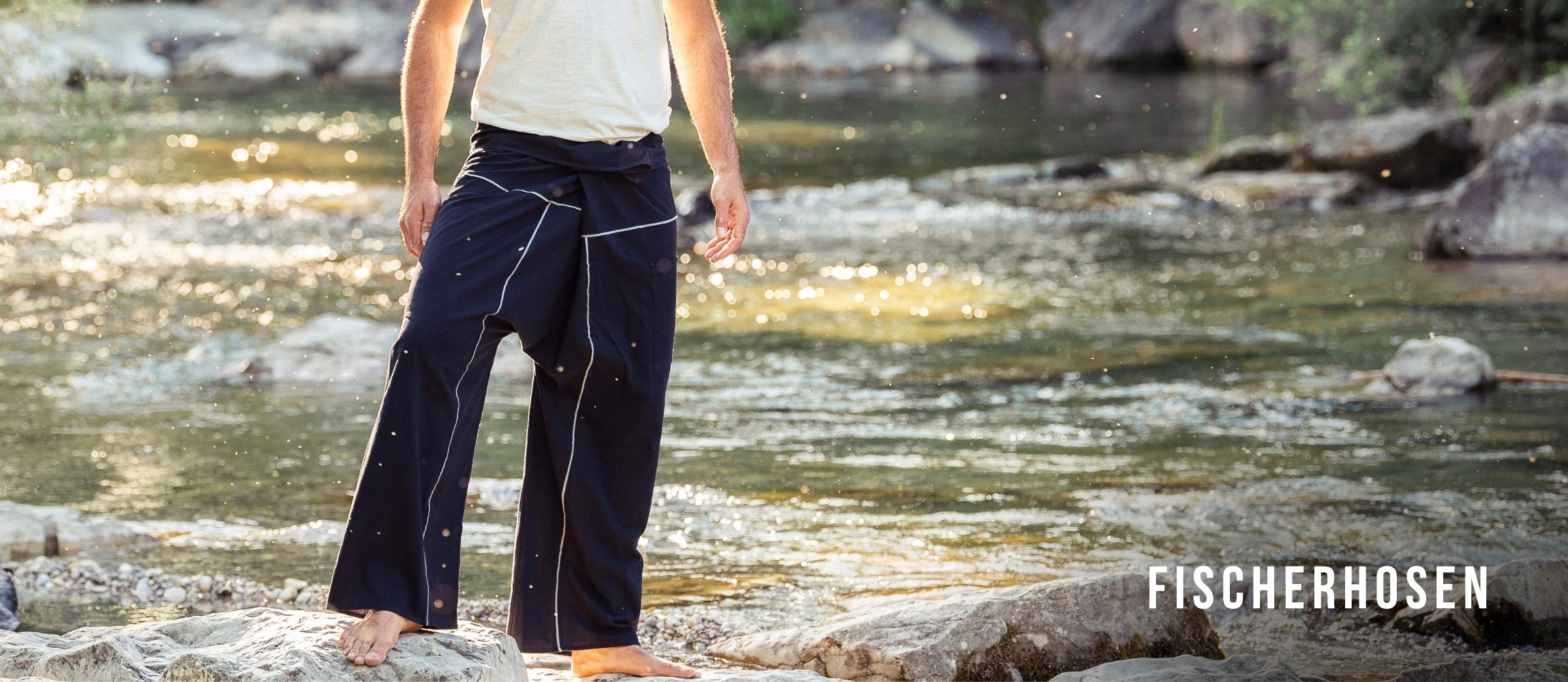 Herren tragen dunkelblaue Fischerhosen barfuß am Flussufer – bequeme weite Freizeithose im Outdoor-Einsatz