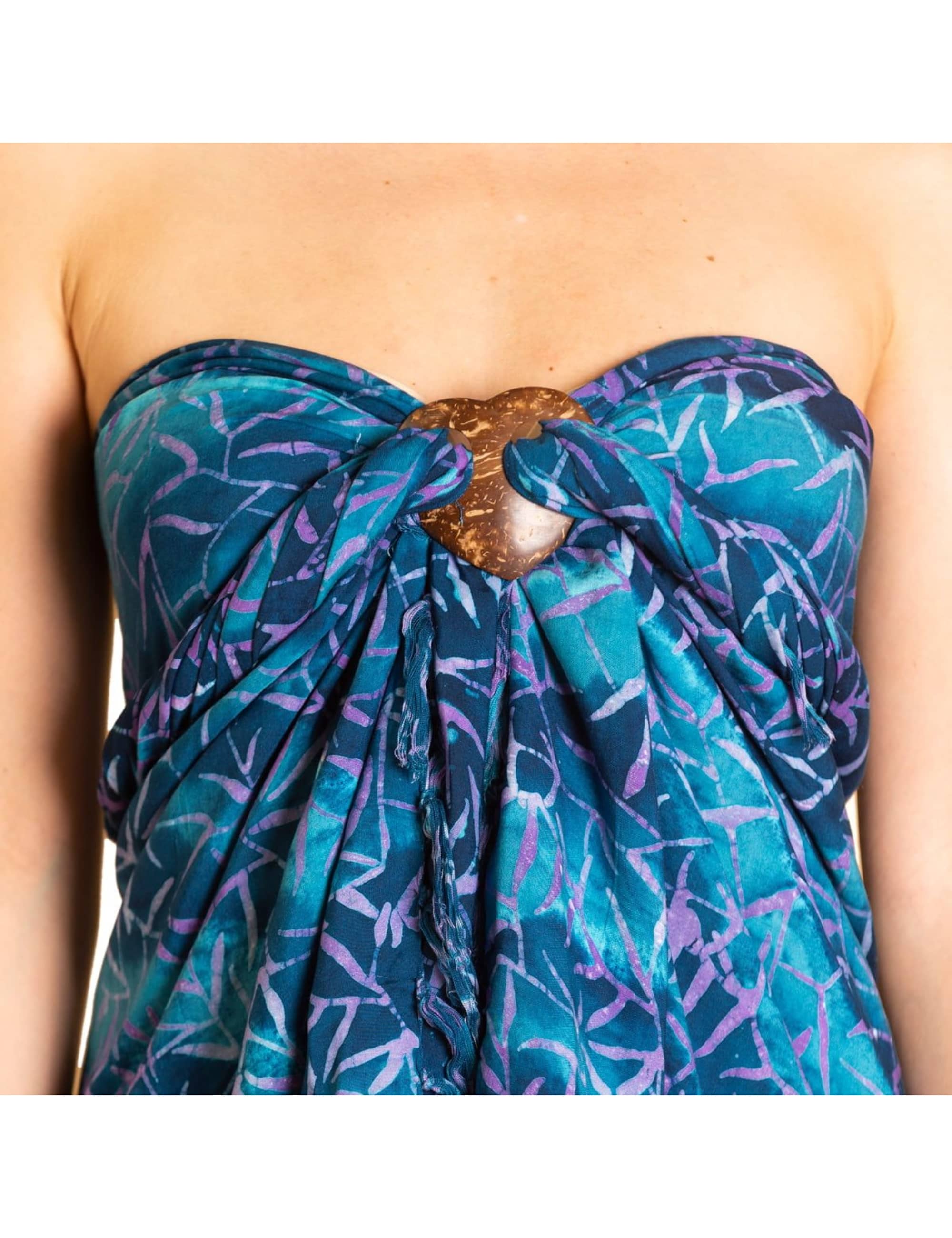 Frau trägt einen blauen batik Sarong als trägerloses Kleid, der vorne mit einem herzförmigen Sarongbinder aus Kokosnuss befestigt ist.