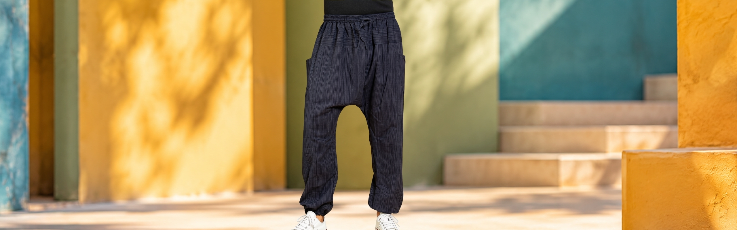 Model wearing dark blue harem trousers with fine texture, dropped crotch, tie waist and pockets
