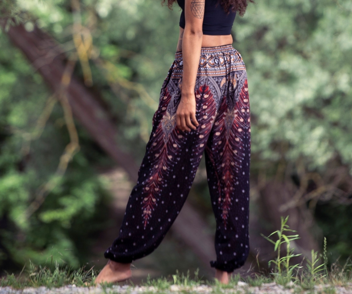 Model wearing loose women's harem trousers with feather print in black and burgundy, boho style