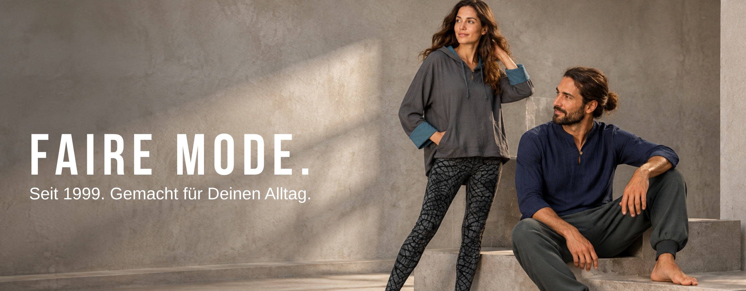 Zwei Models in fairer Damen- und Herren-Loungewear in modernem Indoor-Ambiente, seit 1999 für den Alltag gemacht.