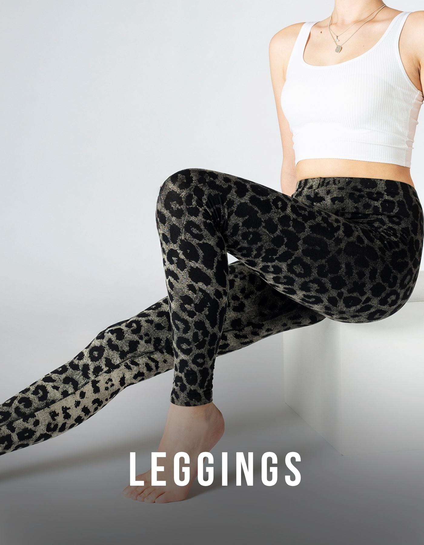Model trägt schwarze und graue Leggings mit Leopardenmuster in sitzender Pose