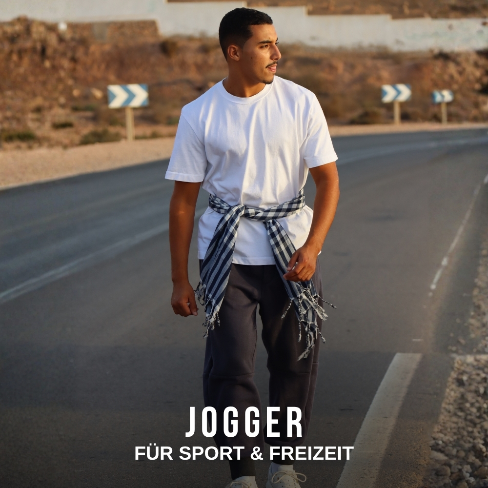 Mann trägt dunkelgraue Herren-Jogger für Sport und Freizeit mit weißem T-Shirt auf einer Straße