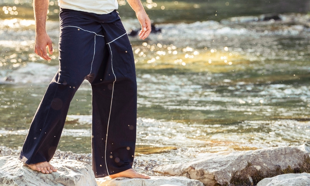 Herren tragen eine dunkelblaue Barfußhose und gehen barfuß auf Felsen am Flussufer