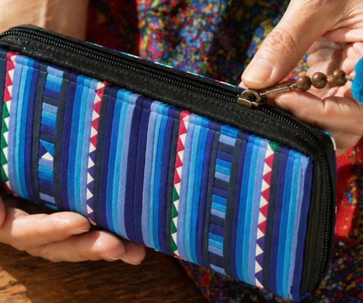 Close-up of a colourful women's zip purse with blue patchwork pattern held in the hand