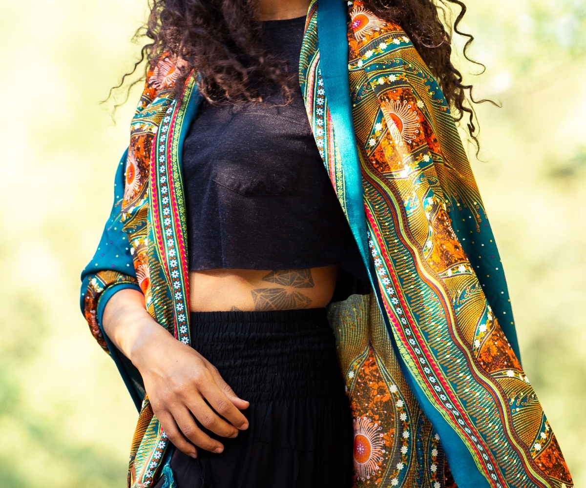 Model trägt einen farbenfrohen Damen-Kimono mit Ethno-Muster in Türkis, Orange und Grün über schwarzem Crop-Top
