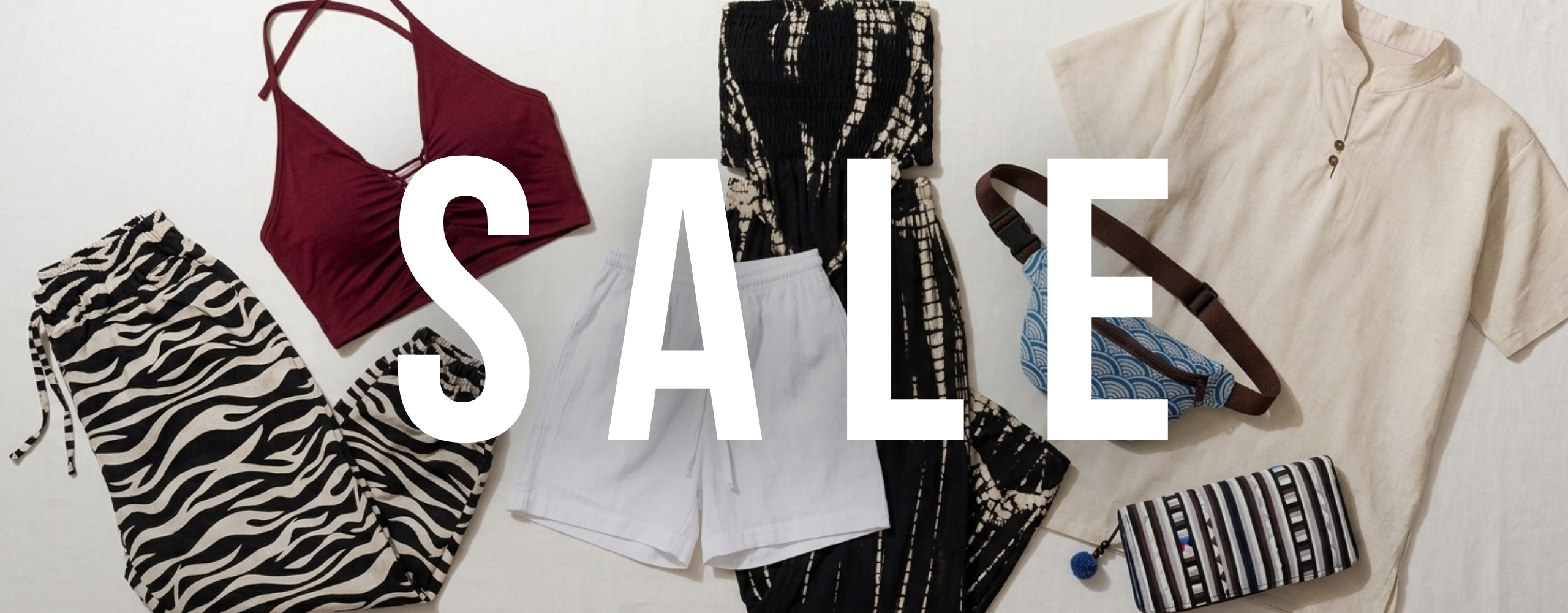 Flatlay mit Sale-Damenmode: Zebra-Hose, bordeauxfarbenes Top, weißer Shorts, schwarz-weißes Kleid, beiges Shirt, Bauchtasche und gestreifte Geldbörse