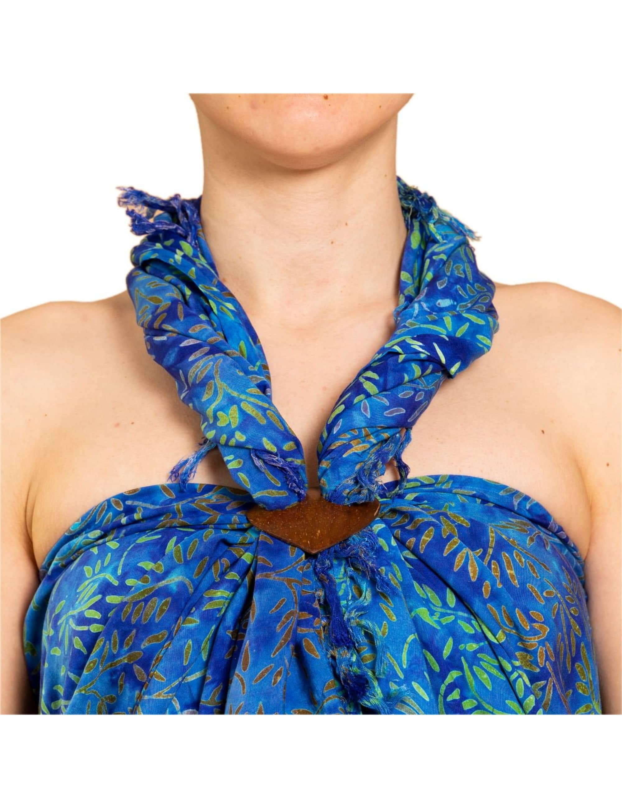 Nahaufnahme eines blau-grün gemusterten batik Sarongs, der als Neckholder-Kleid mit einem herzförmigen Sarongbinder aus Kokosnuss gebunden ist.